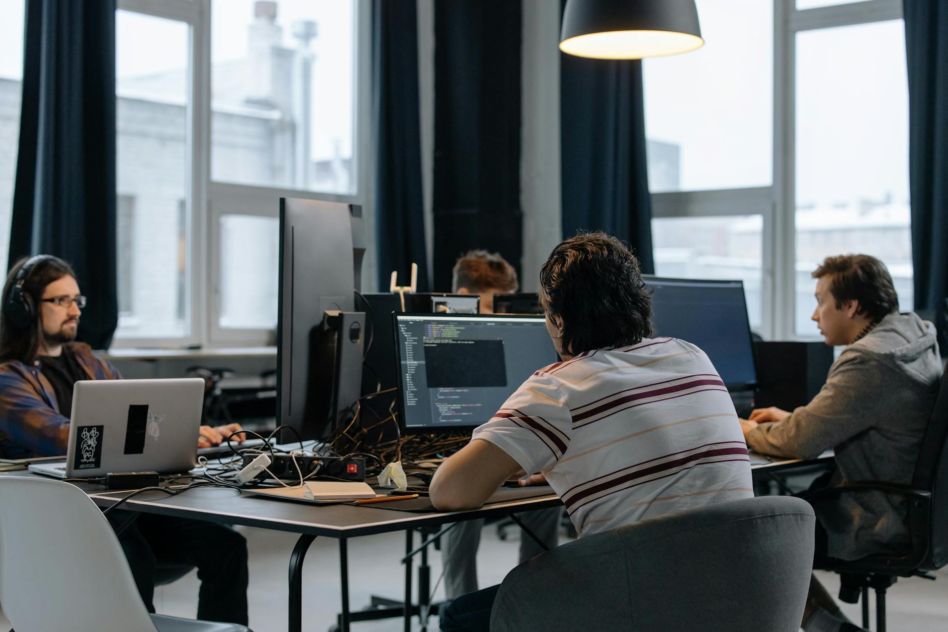 men sitting at the desks in an office and using computers